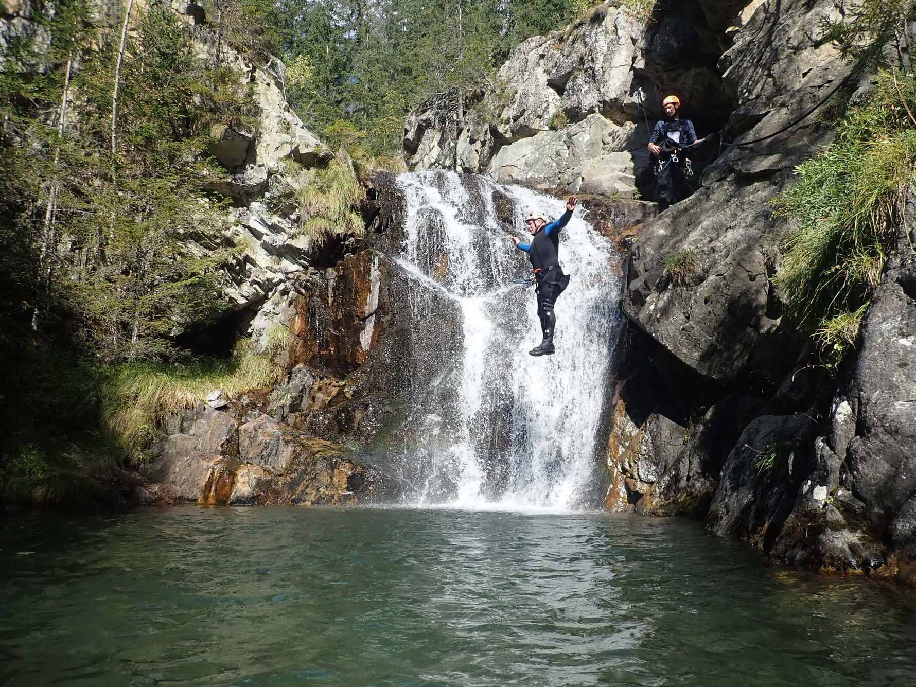 A man jumping off a rock into a canyon pool