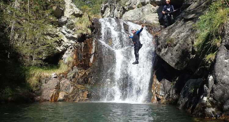 A man jumping off a rock into a canyon pool