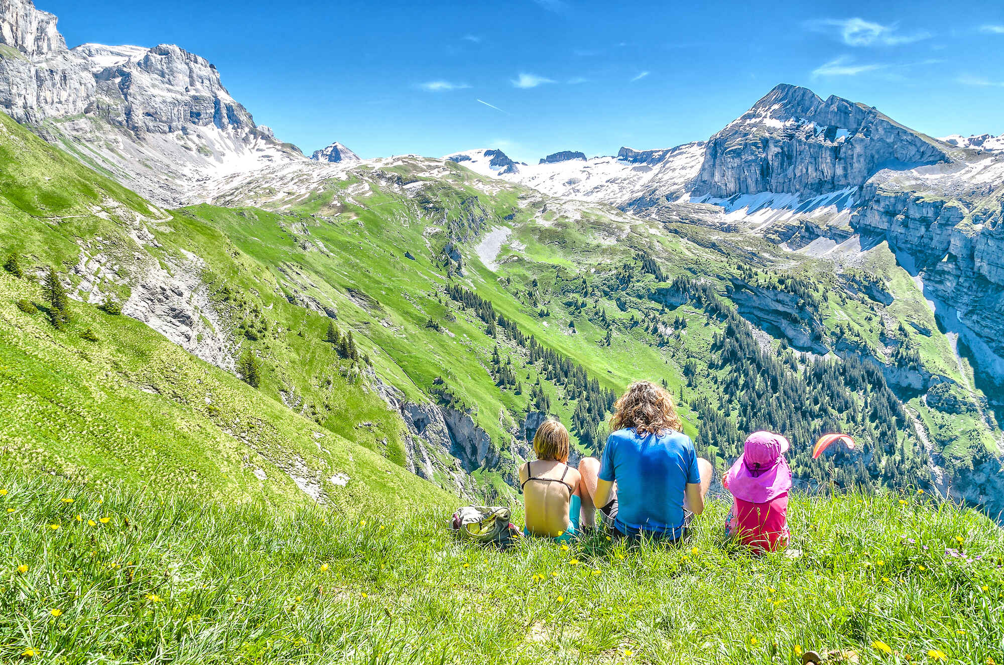 two kids and an adult sitting in the mountains